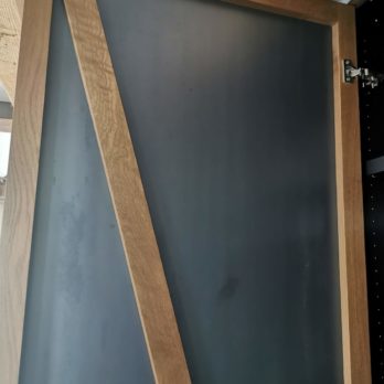 Tür mit einer Cortenstahl-Abdeckung und diagonalen Holzrahmenelementen in einem modernen Design.