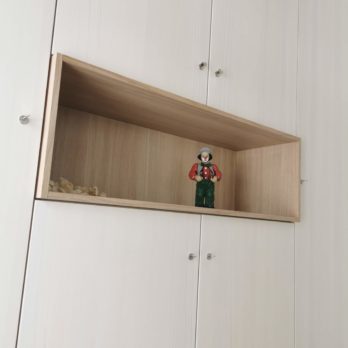 Ein Holzregal mit einer kleinen Figur eines Mannes in traditioneller Kleidung auf einer Holzablage.