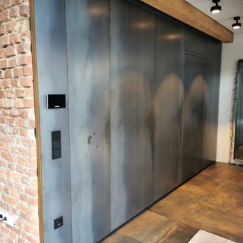 Wandverkleidung aus Metall mit integrierten Lichtquellen und Schaltern in einem Innenraum.