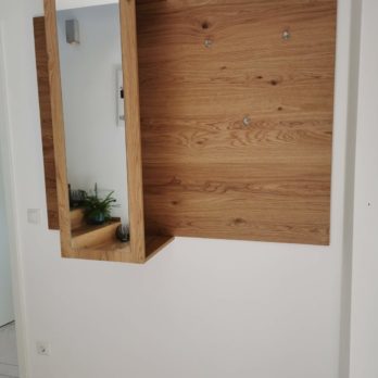 Wandspiegel mit einem Holzregal, das an einer weißen Wand montiert ist.