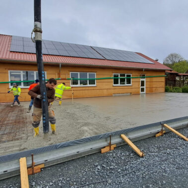 Team beim Betonieren der Bodenplatte – gemeinsamer Einsatz beim Hallenbau.