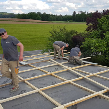 Montage eines großen Holzbalkens auf der Baustelle – Zimmererarbeit in Aktion.