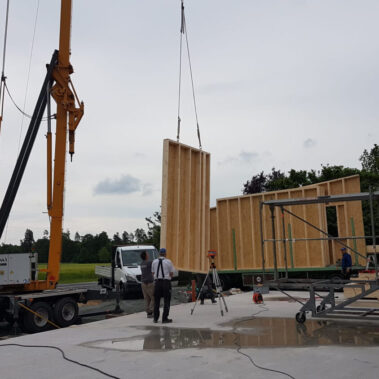 Mitarbeiter befestigt dunkelgraue Holzverschalung an der neuen Halle.