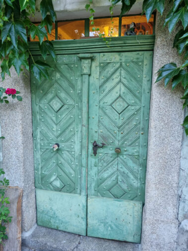 Alte grüne Holztür mit deutlichen Schäden und Verwitterungsspuren vor der Restaurierung