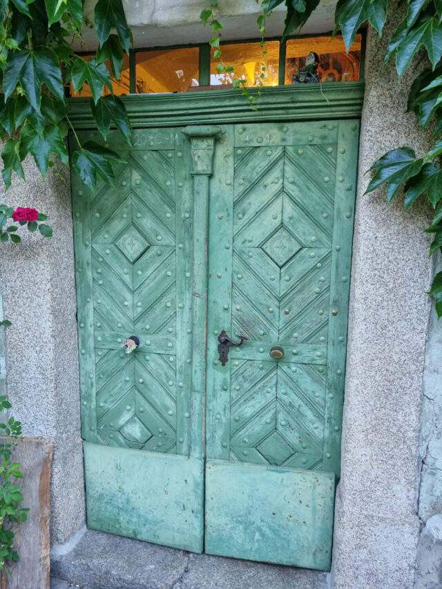 Alte grüne Holztür mit deutlichen Schäden und Verwitterungsspuren vor der Restaurierung