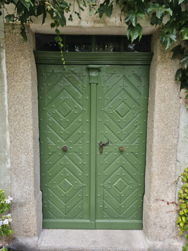 Komplett restaurierte grüne Holztür in neuem Glanz mit historischen Beschlägen.
