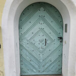 Alte Haustür mit Rundbogen, das Holz ist spröde und in die Jahre gekommen.